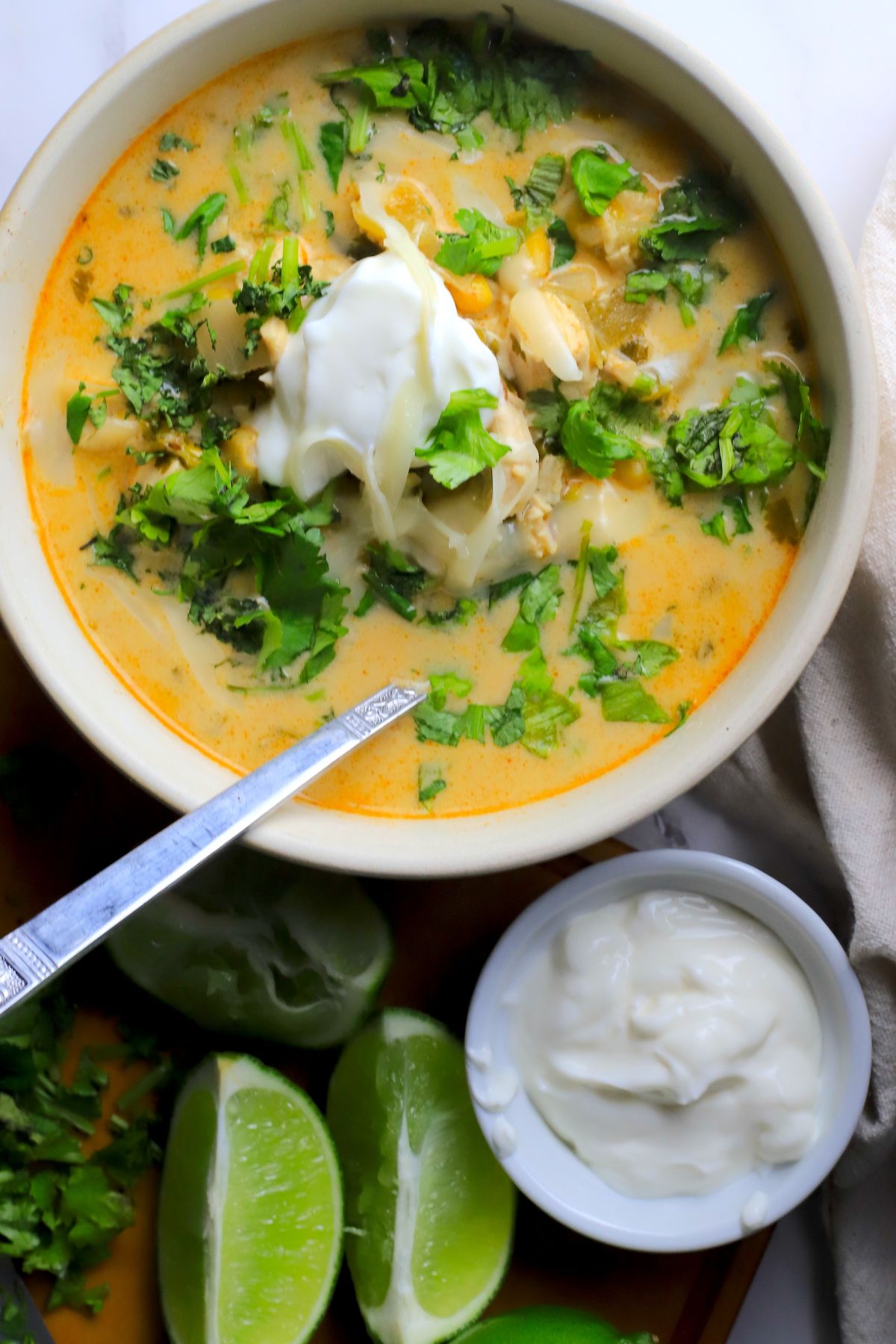 Low carb white chicken chili in a bowl topped with cilantro and sour cream next to some limes.