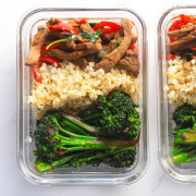 Two glass tupperware containers with the basil beef, cauliflower rice and broccolini.