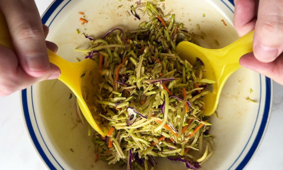 Tossing the asian coleslaw in a large bowl.