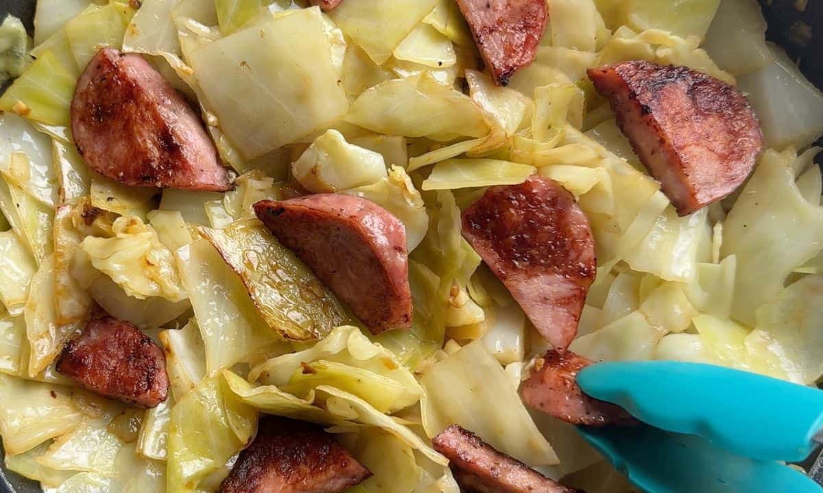 Adding the sausage back into the skillet with the cabbage.
