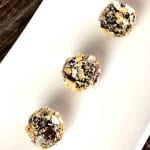 Three chocolate coconut nut balls on a white plate.