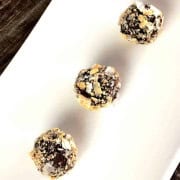 Three chocolate coconut nut balls on a white plate.