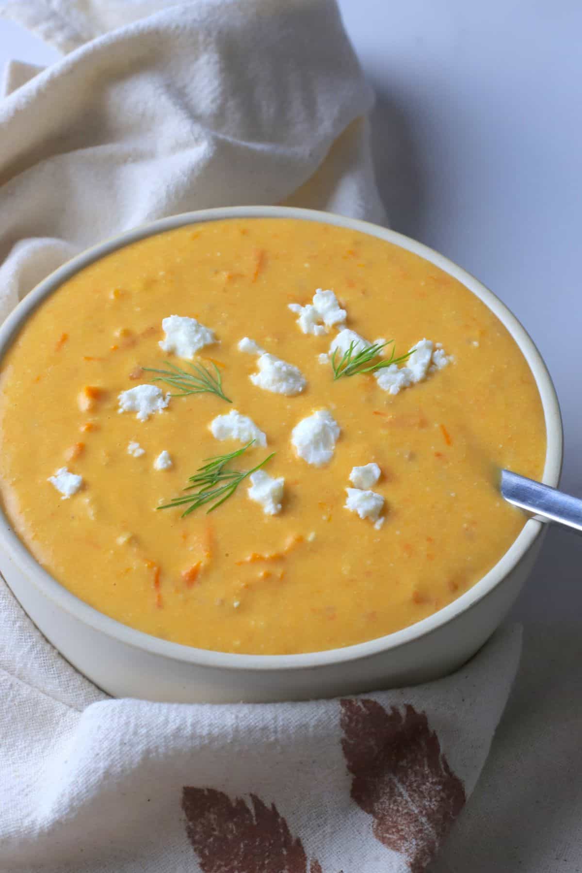 Soup bowl with tomato soup, topped with feta cheese and dill.