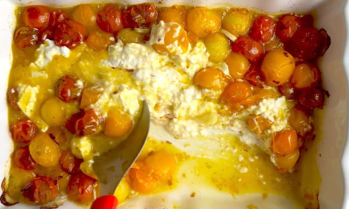 Mixing the tomatoes and feta in the casserole dish.