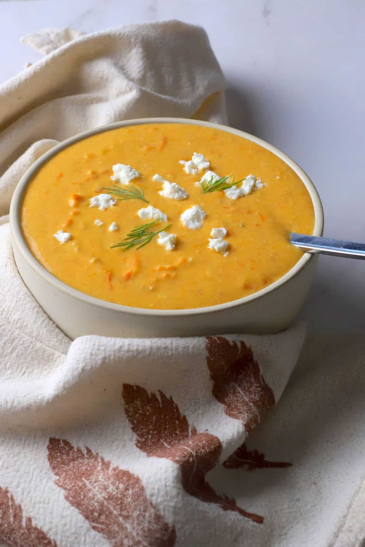 Soup bowl with tomato soup, topped with feta cheese and dill.