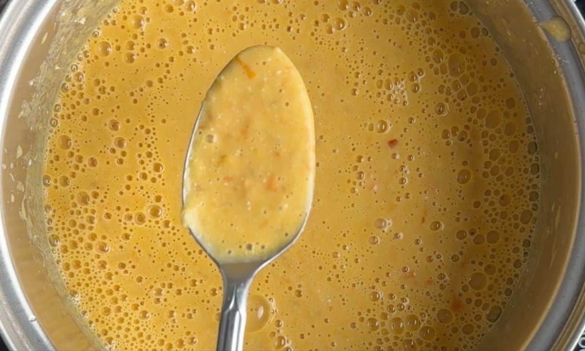 Spoon with soup above the pot.