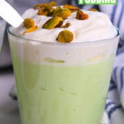 High protein pistachio pudding in a glass cup topped with whipped cream and crushed pistachios.