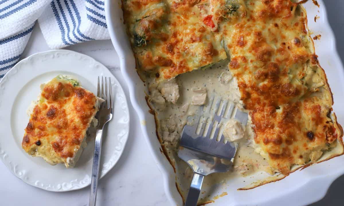 A slice of low carb italian chicken veggie casserole on a plate with the casserole dish next to it.
