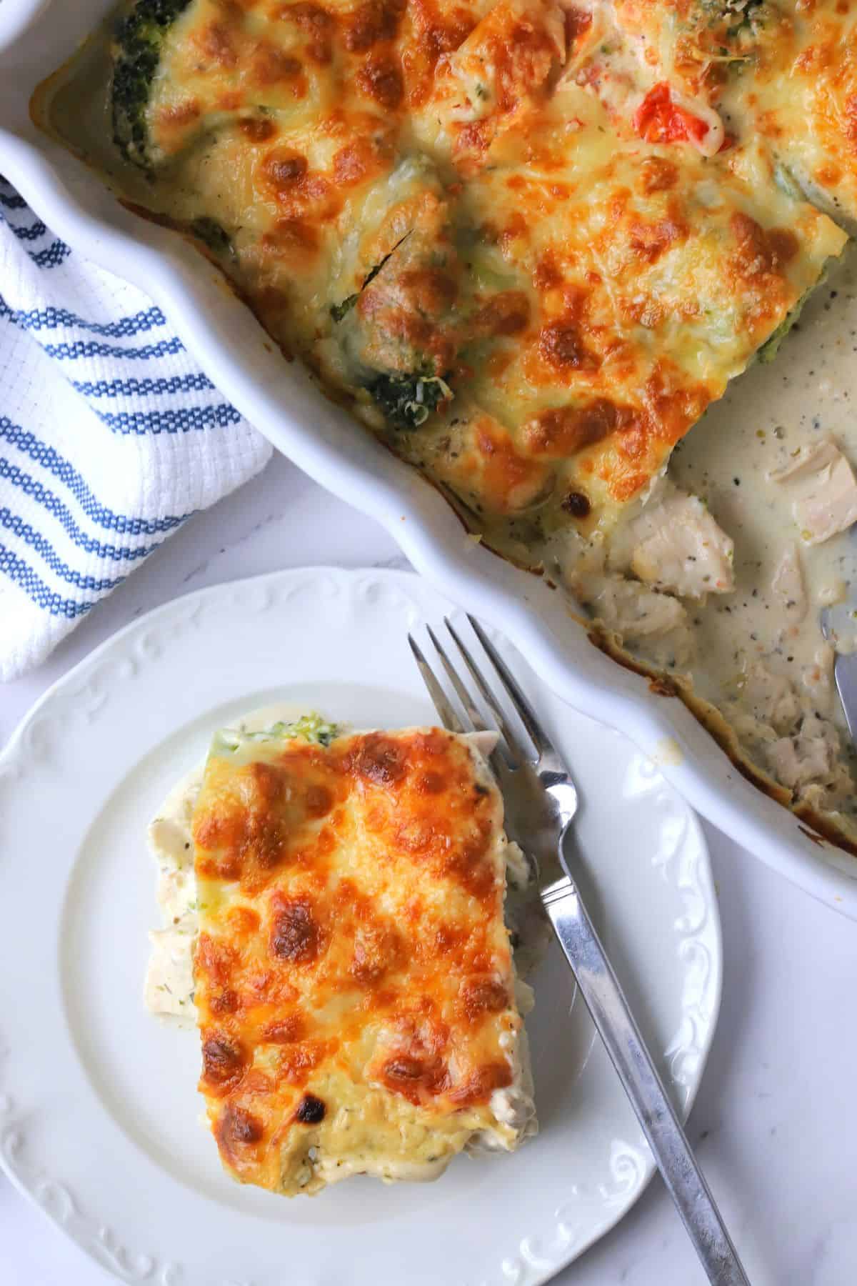 A slice of low carb italian chicken veggie casserole on a plate with the casserole dish next to it.