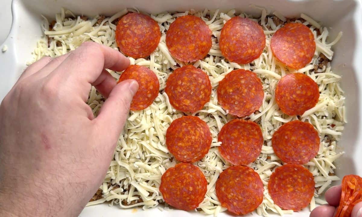 Adding the pepperoni slices on the casserole dish.