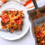 Low carb pizza casserole slice on a plate with the casserole next to it.