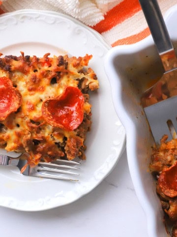 Low carb pizza casserole slice on a plate with the casserole next to it.