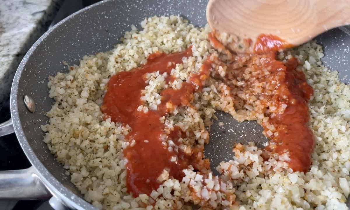 Frying the cauliflower rice with some tomato sauce.