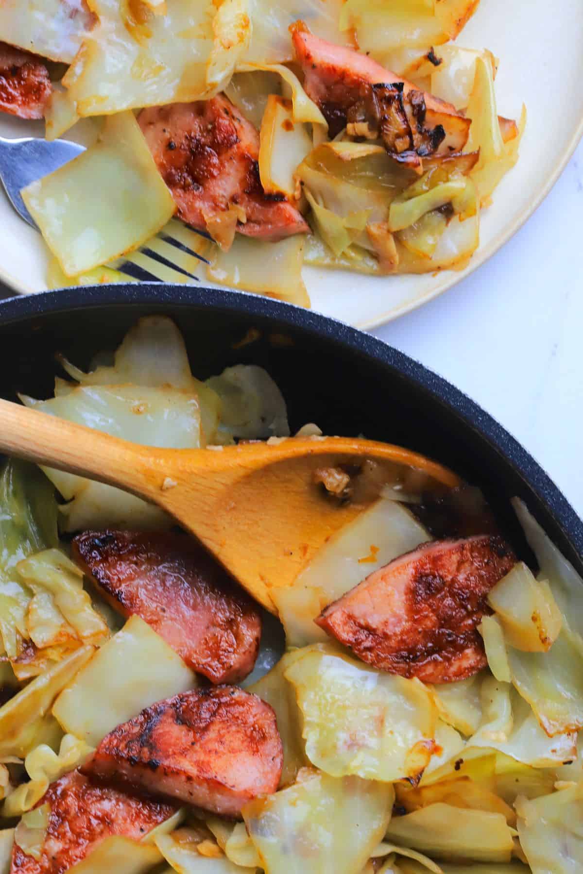 Cabbage and sausage in a skillet and on a plate.