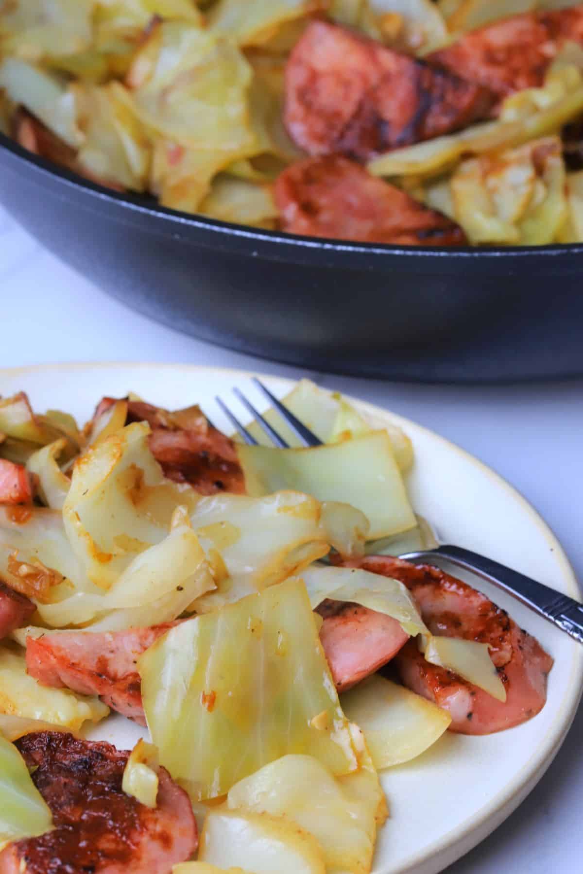 Cabbage and sausage in a skillet and on a plate.