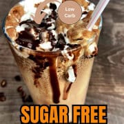 Large glass with sugar free cappuccino topped with whipping cream and chocolate with a plastic straw.