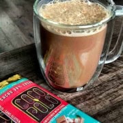 Sugar free spicy hot chocolate in a glass mug next to chocolate bars.