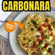 Bowl of dairy free spaghetti carbonara topped with pancetta and chopped parsley.