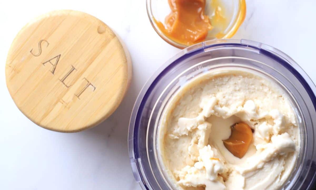 Ninja creami pint with salted caramel ice cream with salt and a small bowl of caramel on the side.