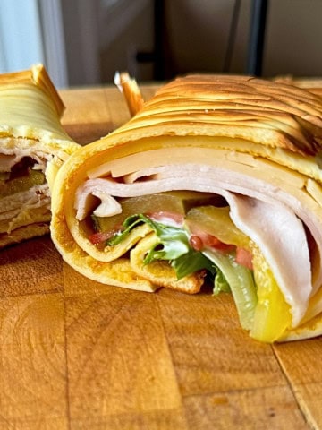 2 ingredient cottage cheese wrap on a cutting board rolled and sliced in half.