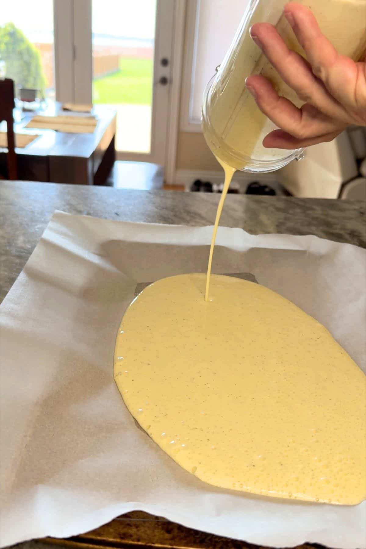 Pouring the mixture on to the parchment lined baking sheet.