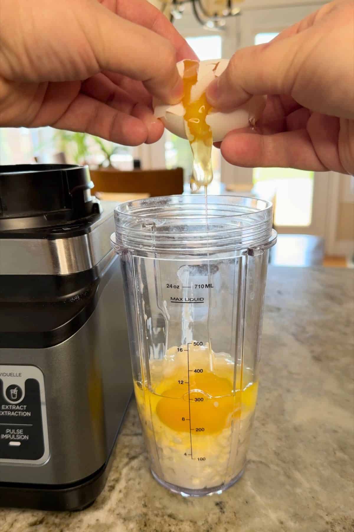 Cracking an egg over the blender cup.