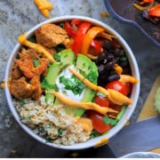 Low carb chicken fajita bowl filled with chicken, peppers, black beans, tomatoes, cauliflower rice and an avocado.