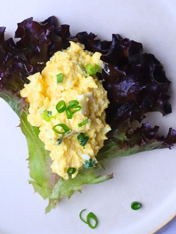 Low carb egg salad on a lettuce leaf topped with slices of green onion.