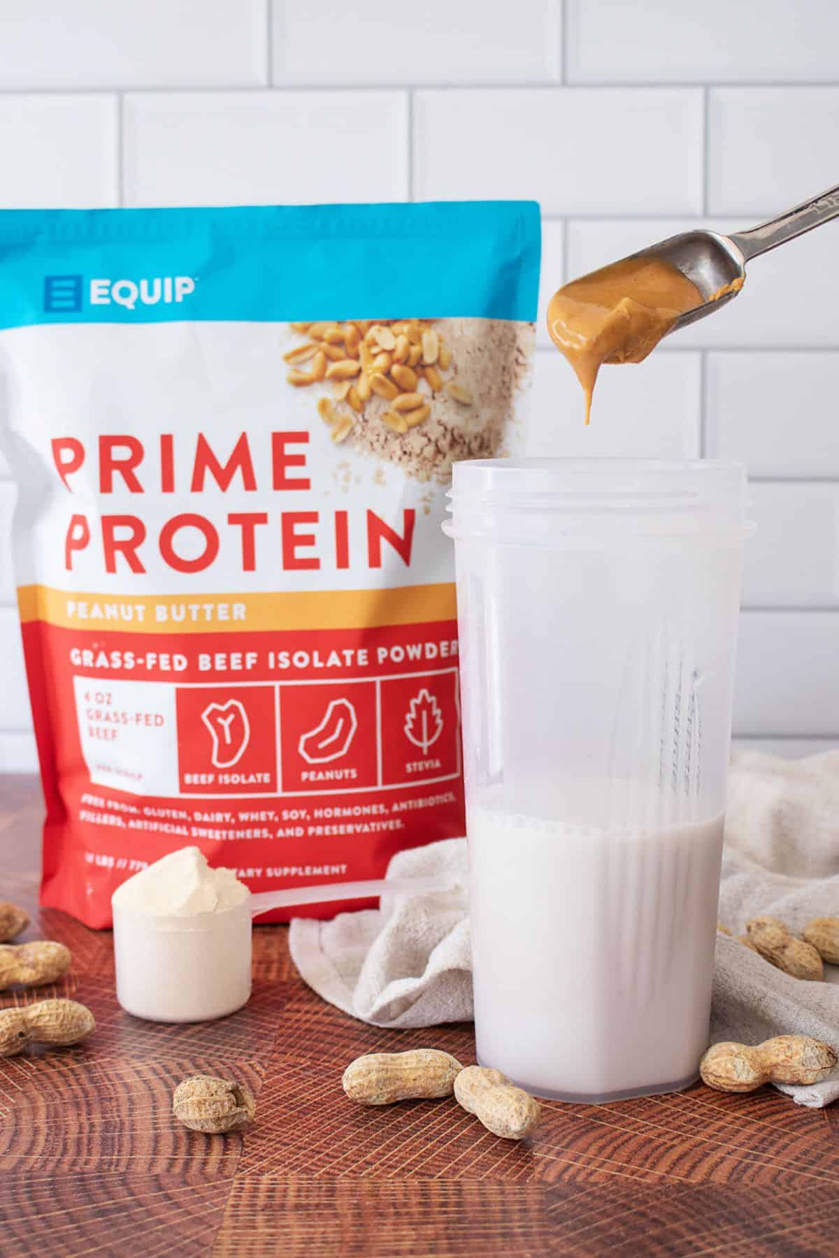 Photo of prime protein powder with cup and spoon with peanut butter.