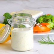 Greek yogurt protein ranch in a mason jar next to a plate of vegetables with a ranch dip.
