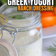Greek yogurt protein ranch in a mason jar next to a plate of vegetables with a ranch dip image for pinterest.