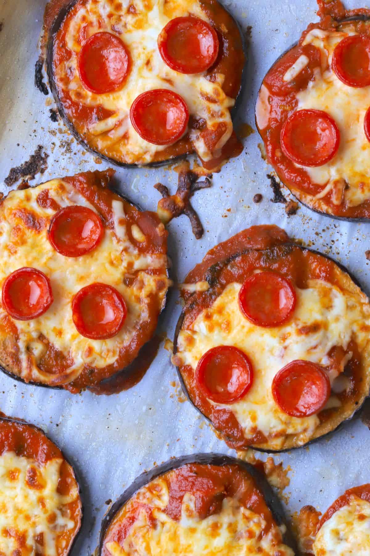 Low carb eggplant pizzas on a parchment lined baking sheet.