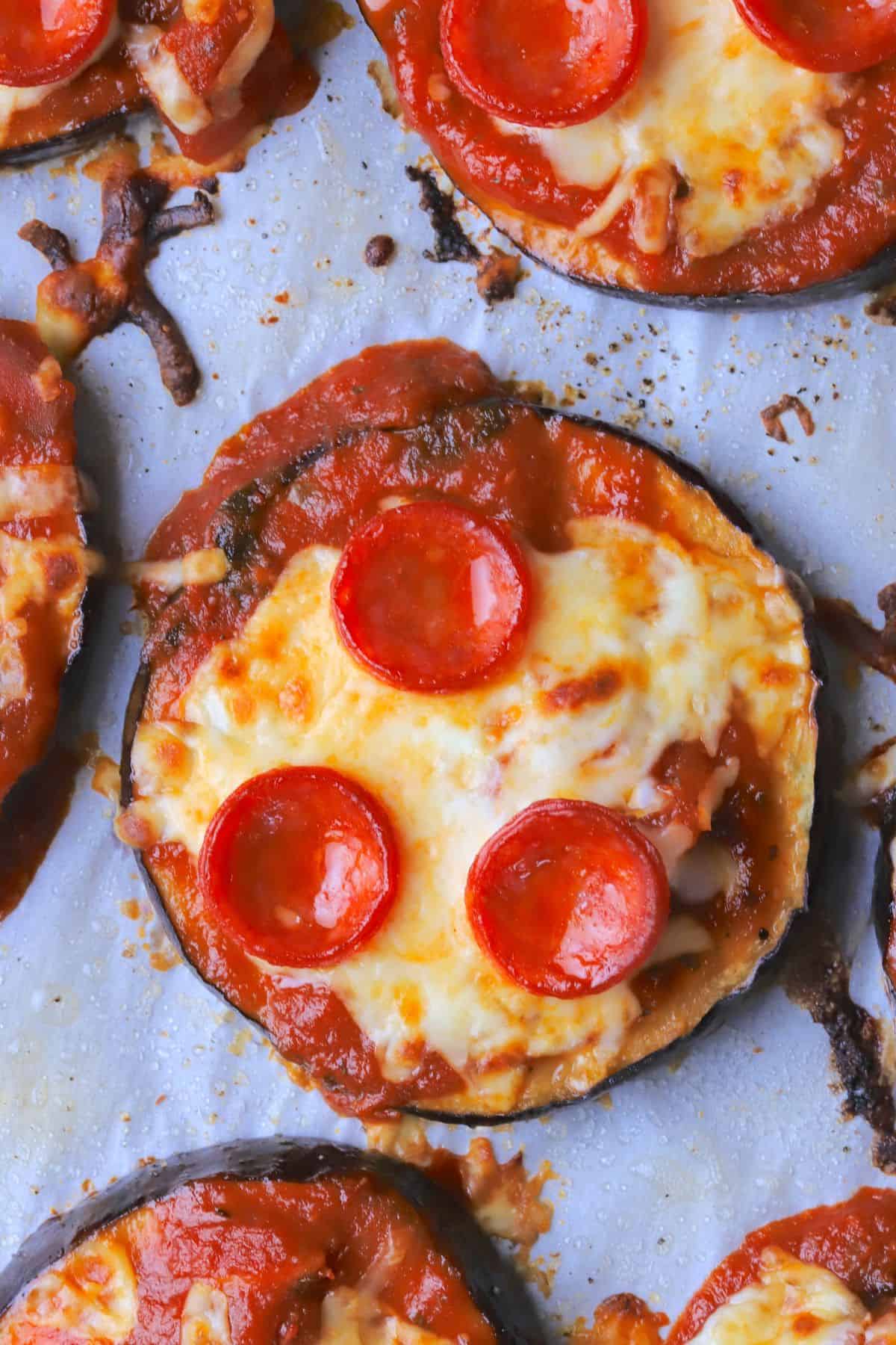 Low carb eggplant pizzas on a parchment lined baking sheet.