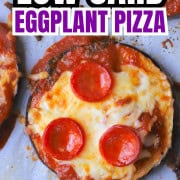 Low carb eggplant pizzas on a parchment lined baking sheet for a pinterst image.