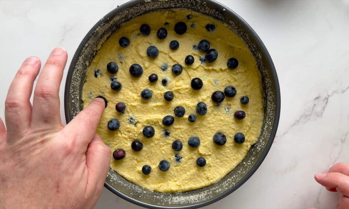 Pressing the blueberries into the cake batter.
