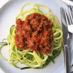 Zucchini noodles on a plate topped with a meat sauce.