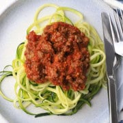 Zucchini noodles on a plate topped with a meat sauce.