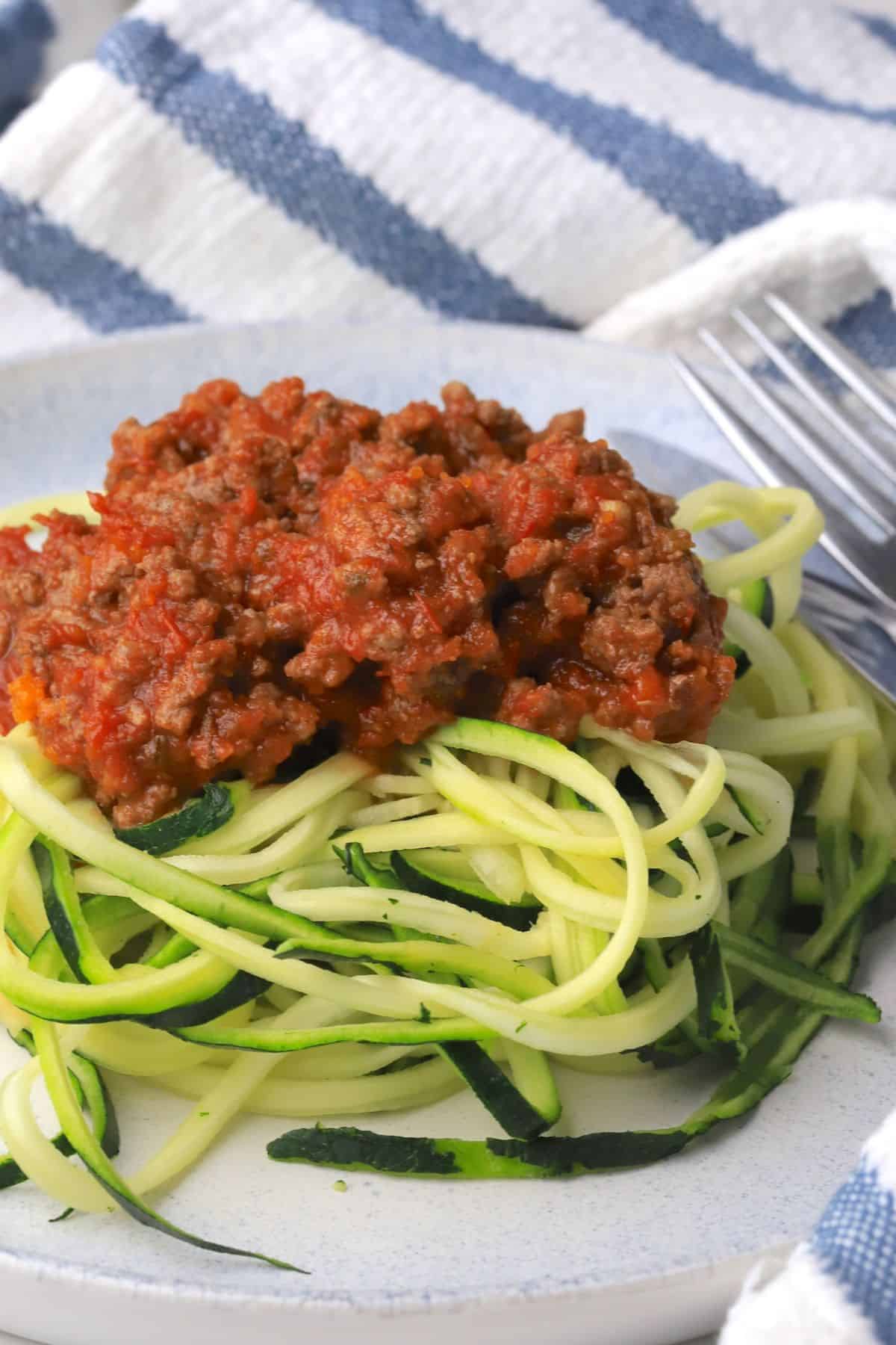 Zucchini noodles on a plate topped with a meat sauce.