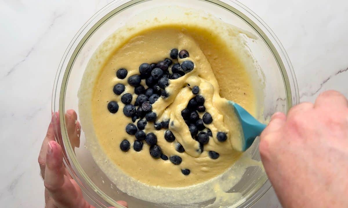 Folding the fresh blueberries into the batter.