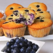 Blueberry cottage cheese muffins next to a bowl of fresh blueberries.
