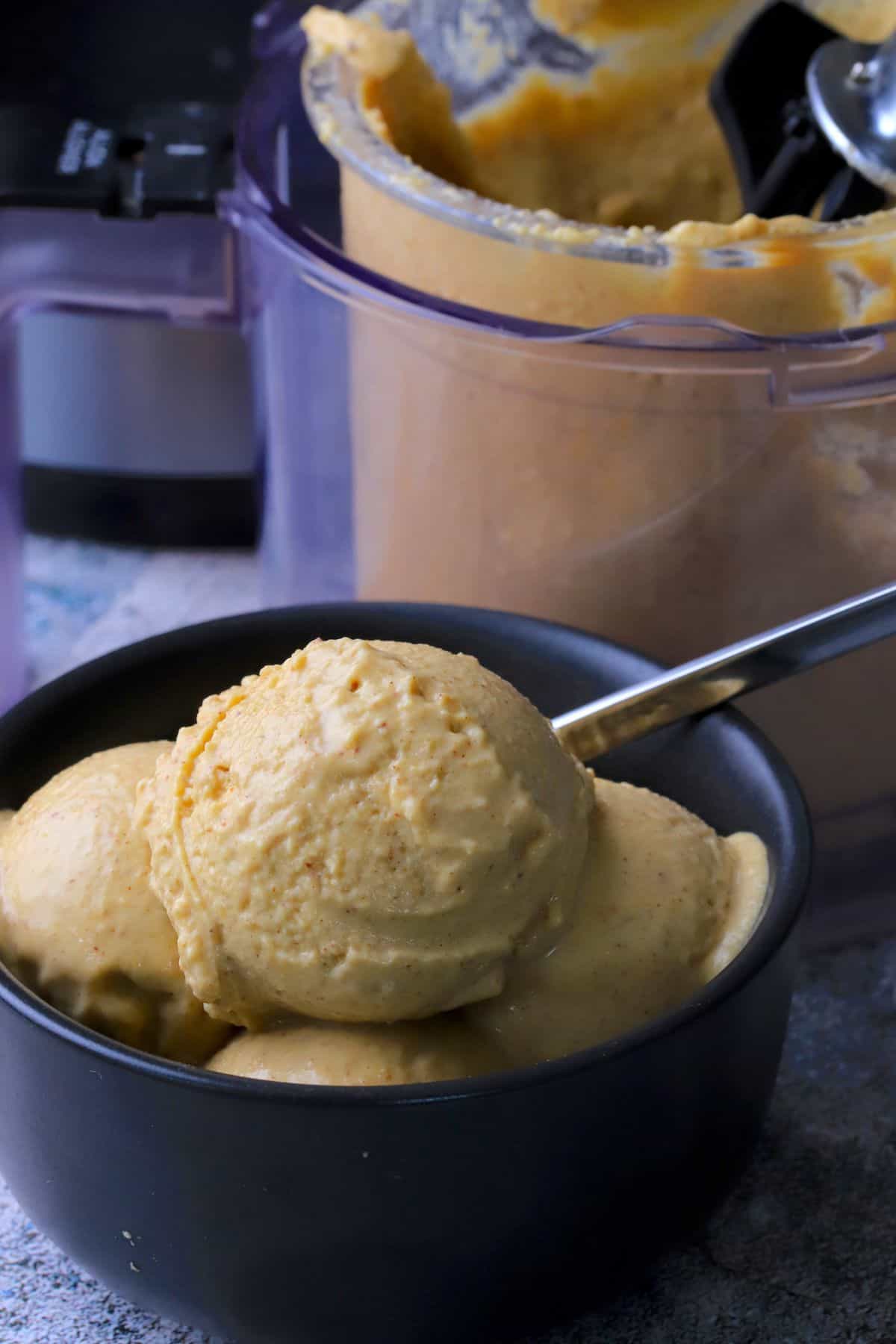 Chickpea cinnamon ice cream in a bowl next to the ninja creami pint.