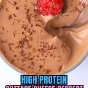 A high protein cottage cheese chocolate mousse dessert in a glass cup topped with raspberries and chocolate shavings.