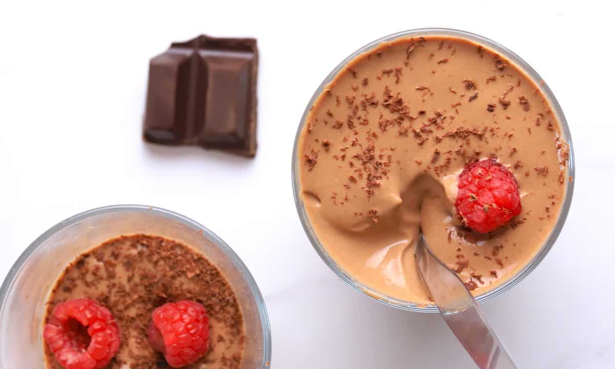 High protein cottage cheese dessert chocolate mousse in a glass cup topped with raspberries and chocolate shavings.