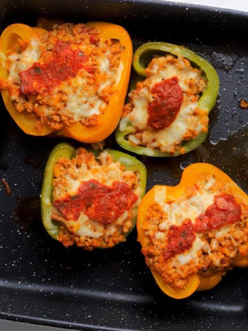 Low carb stuffed peppers topped with mozzarella and marinara sauce in a casserole dish.