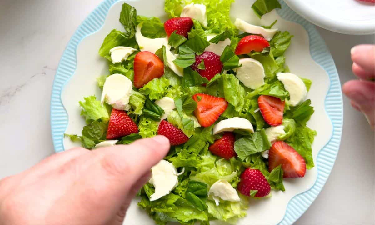 Preparing the low carb strawberry caprese salad.