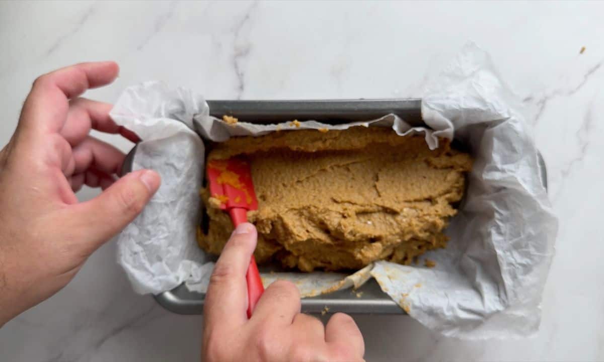 Smoothing the top of the batter in a loaf pan.