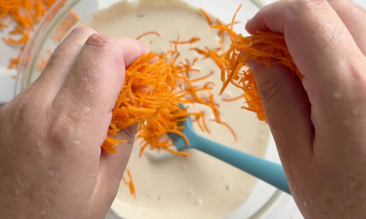 Adding the shredded carrots to the wet mixture.