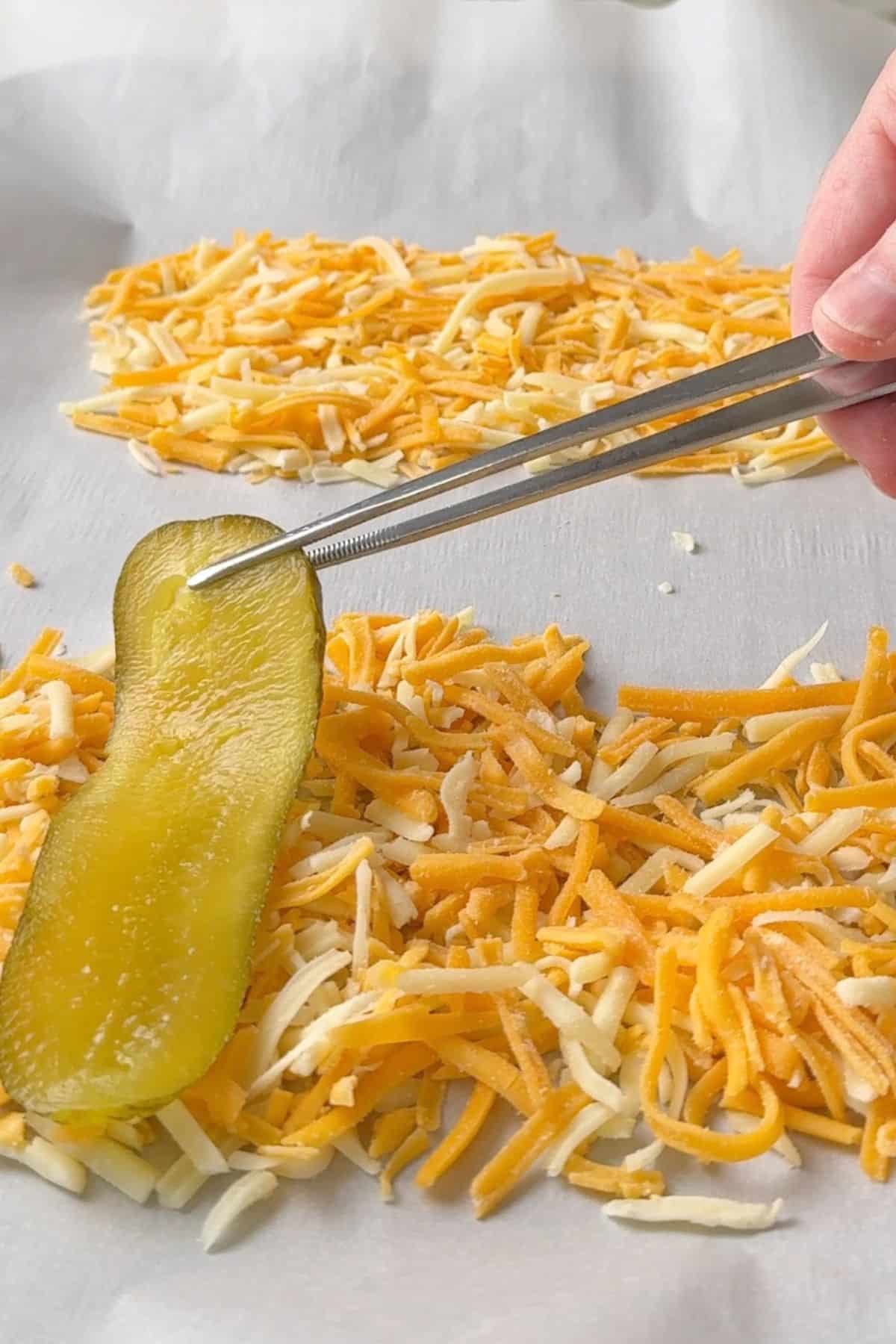 Topping the shredded cheese with a pickle.