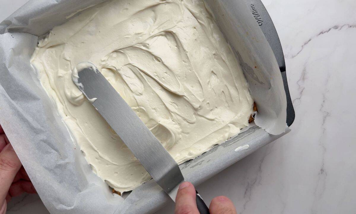 Spreading the cream cheese layer in the pan.