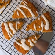 Gluten Free High Protein Low carb pumpkin spice scones drizzled with a glaze on a cooling rack.